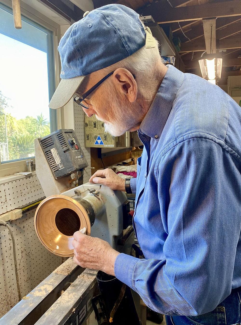 Gerald carves a wooden bowl on a lathe.